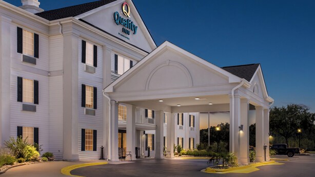 A large, white hotel with a prominent entrance and a sign reading "Quality Inn."