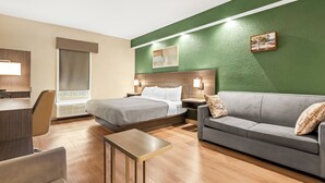 A hotel room with a bed, a sofa, a desk, and a chair.