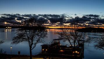 A lakeside dock with a small building, calm water, and a sunset in the background.