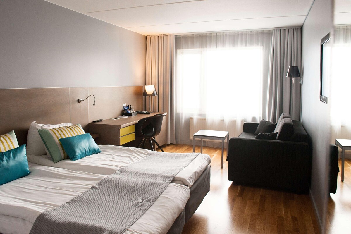 Habitació d'hotel amb llit, escriptori, cadira i sofà.