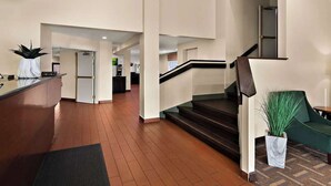 A spacious lobby with a reception desk, a staircase, and a green seating area. - Quality Inn Memphis Northeast near I-40 (Memphis)
