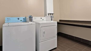 A laundry room with two Whirlpool washers and dryers, a water dispenser, and a tiled floor. - Quality Inn Memphis Northeast near I-40 (Memphis)