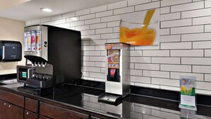 A self-service beverage station with a coffee machine and a drink dispenser, set against a tiled wall. - Quality Inn Memphis Northeast near I-40 (Memphis)