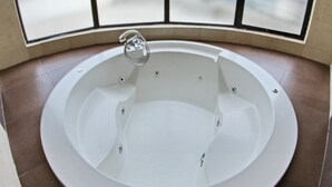 Une salle de bain moderne avec une baignoire sur pieds, une grande fenêtre avec des panneaux de verre dépoli et un sol carrelé.