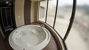 A modern bathroom with a freestanding bathtub, a glass shower enclosure, and a view of the outdoors.