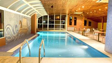 Una piscina techada, sillones reclinables de piscina