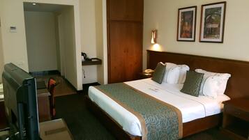Een hotelkamer met een bed, bureau, televisie en een kledingkast.