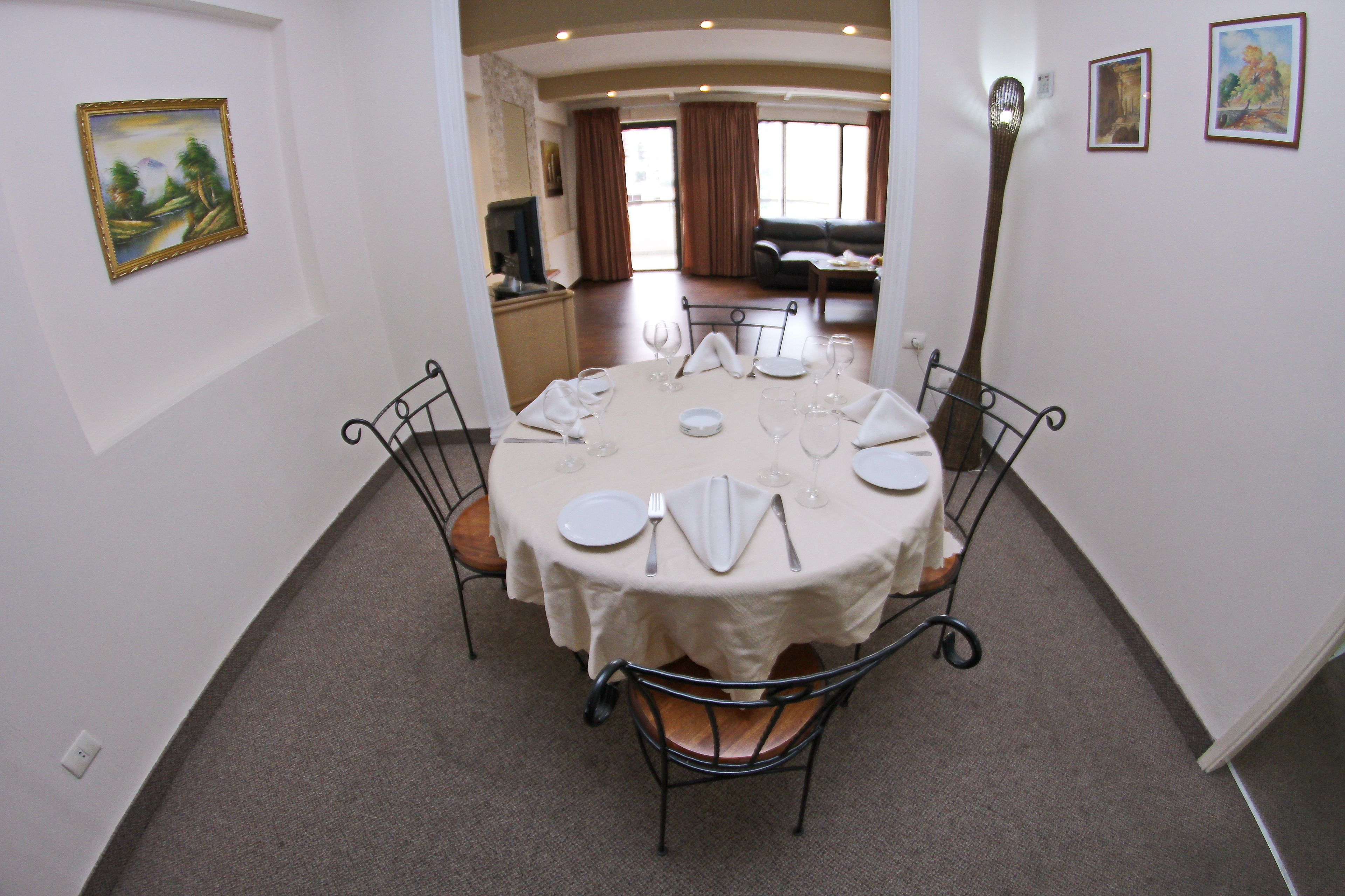 A dining area with a round table set for four, surrounded by metal chairs.