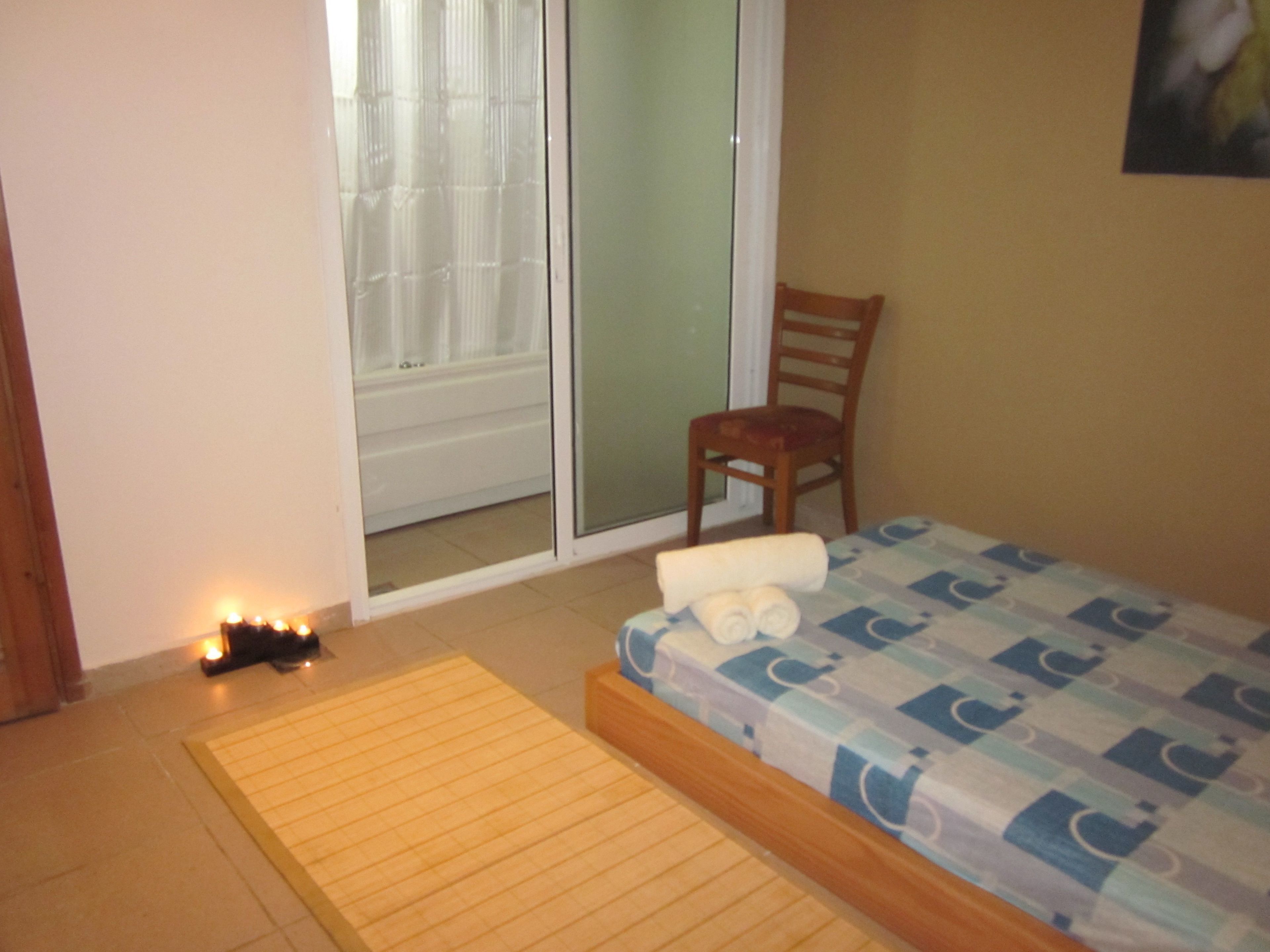 Un dormitorio con cama, una silla, un ventanal corredero y una alfombra pequeña.