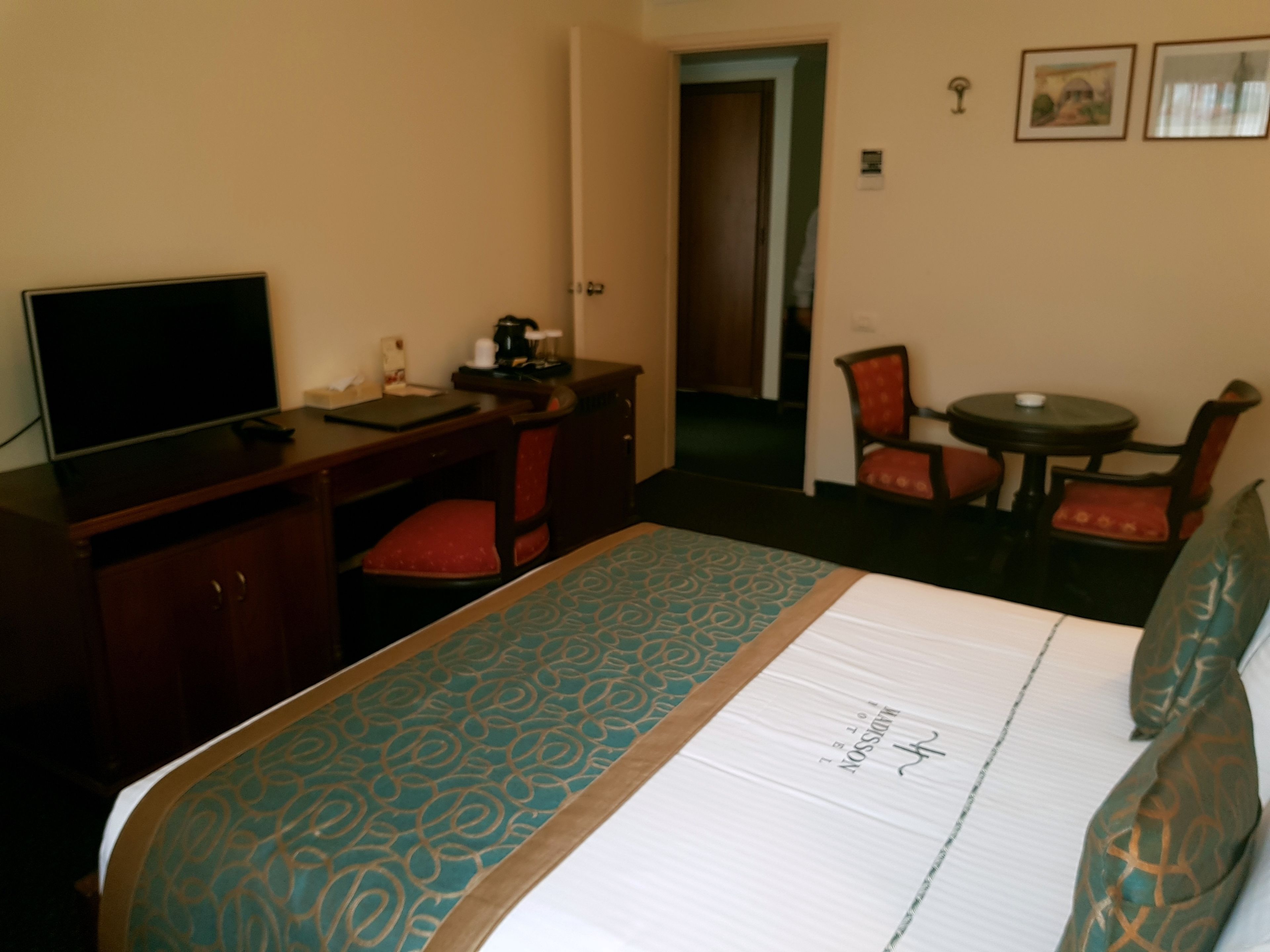 Een hotelkamer met een bed, een bureau, een stoel, een televisie en een klein tafeltje.