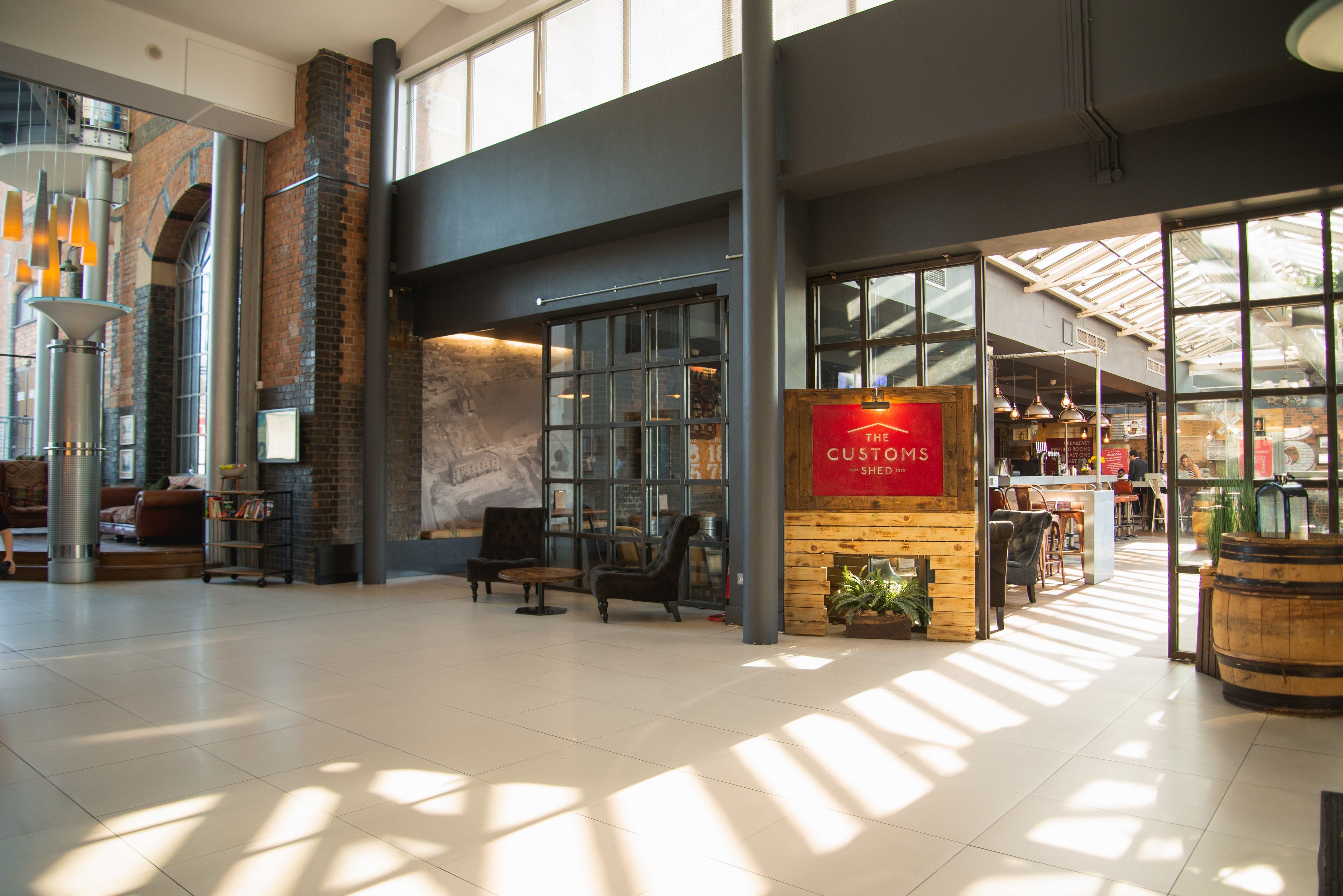 Un vestíbul ample amb un disseny modern, que compta amb una zona de seients, una cafeteria i grans finestres que deixen entrar llum natural.