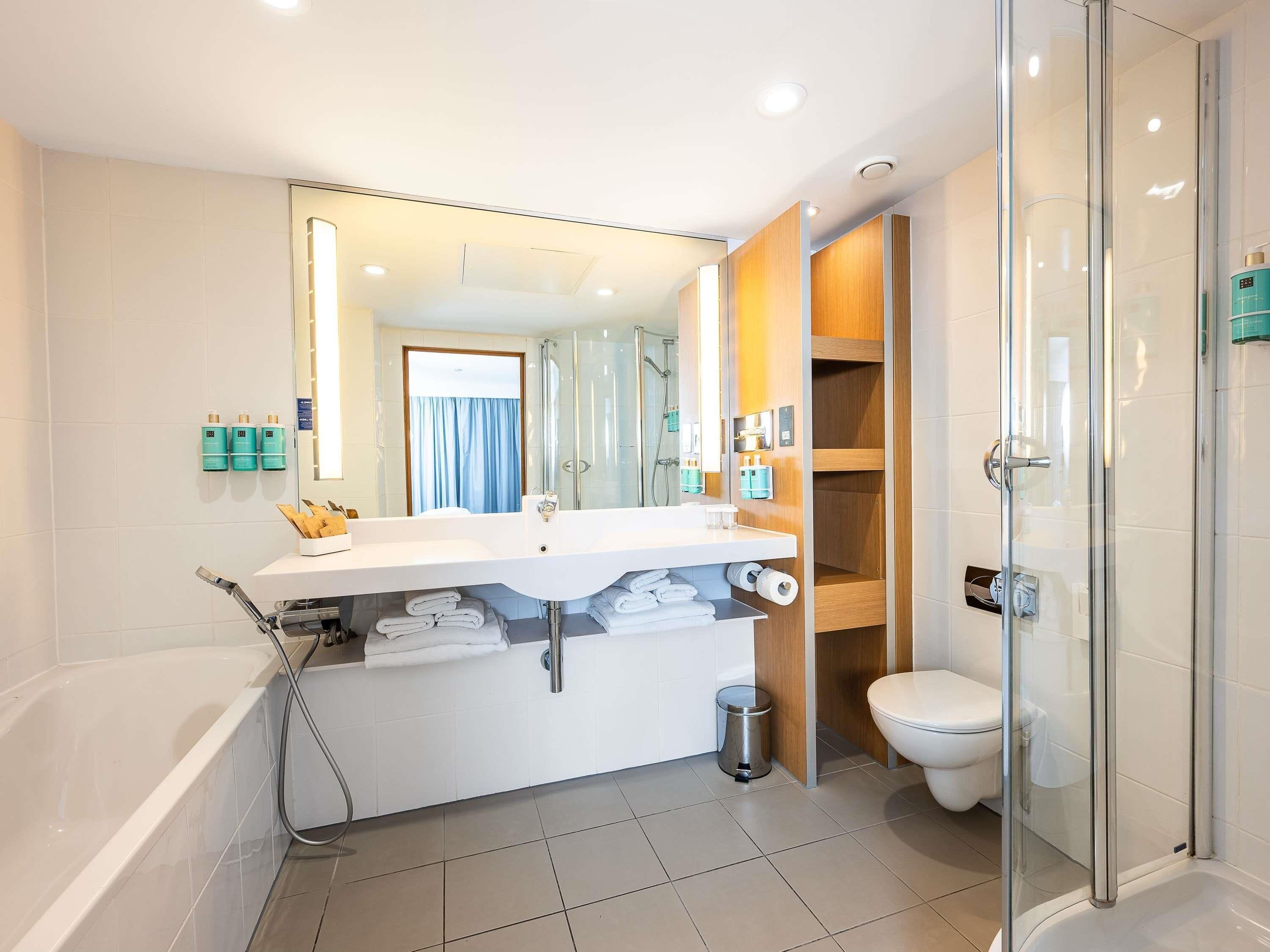 A modern bathroom with a bathtub, toilet, and shower area.