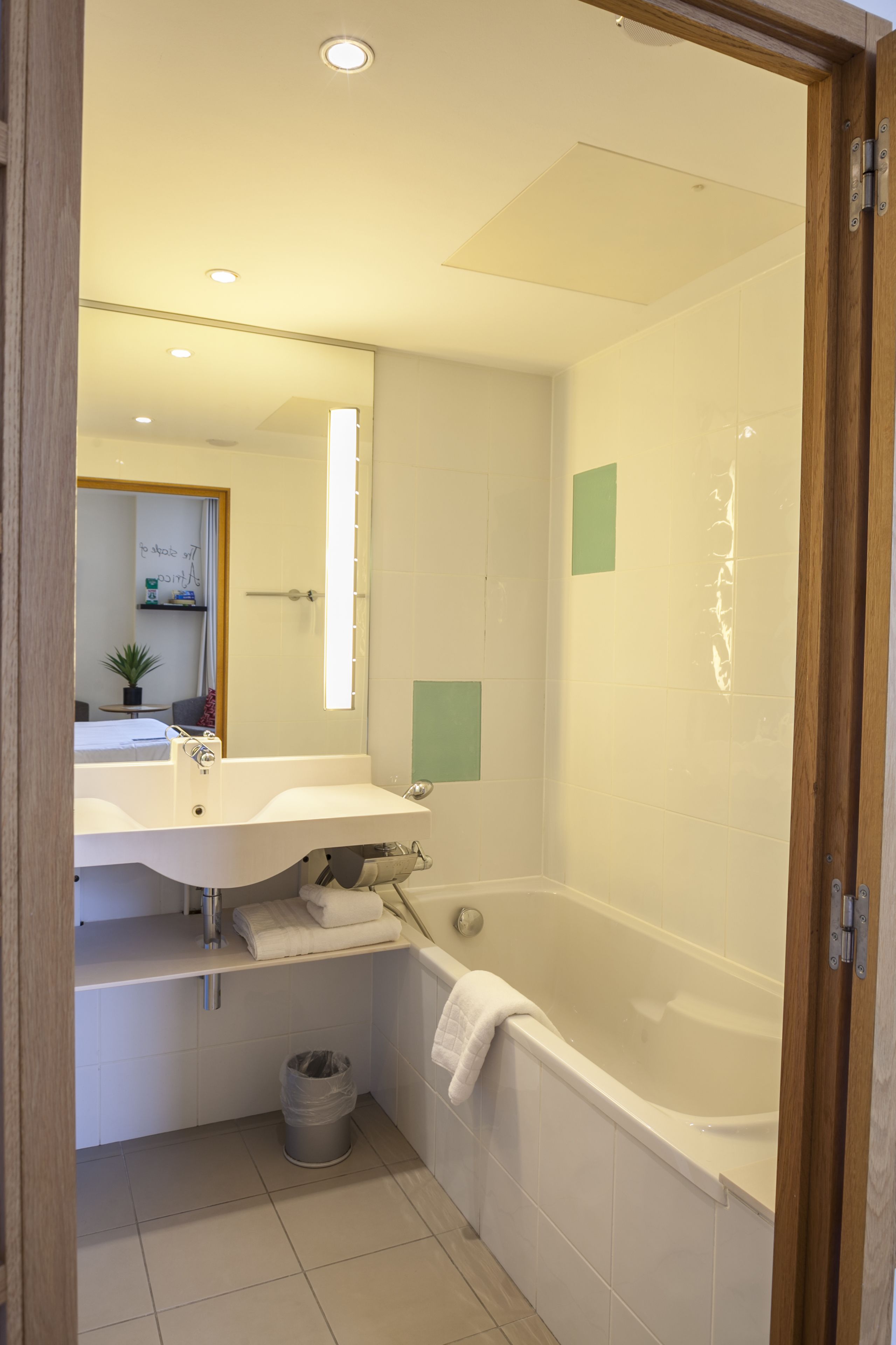 Une salle de bain avec une baignoire, un lavabo, un miroir et une poubelle.
