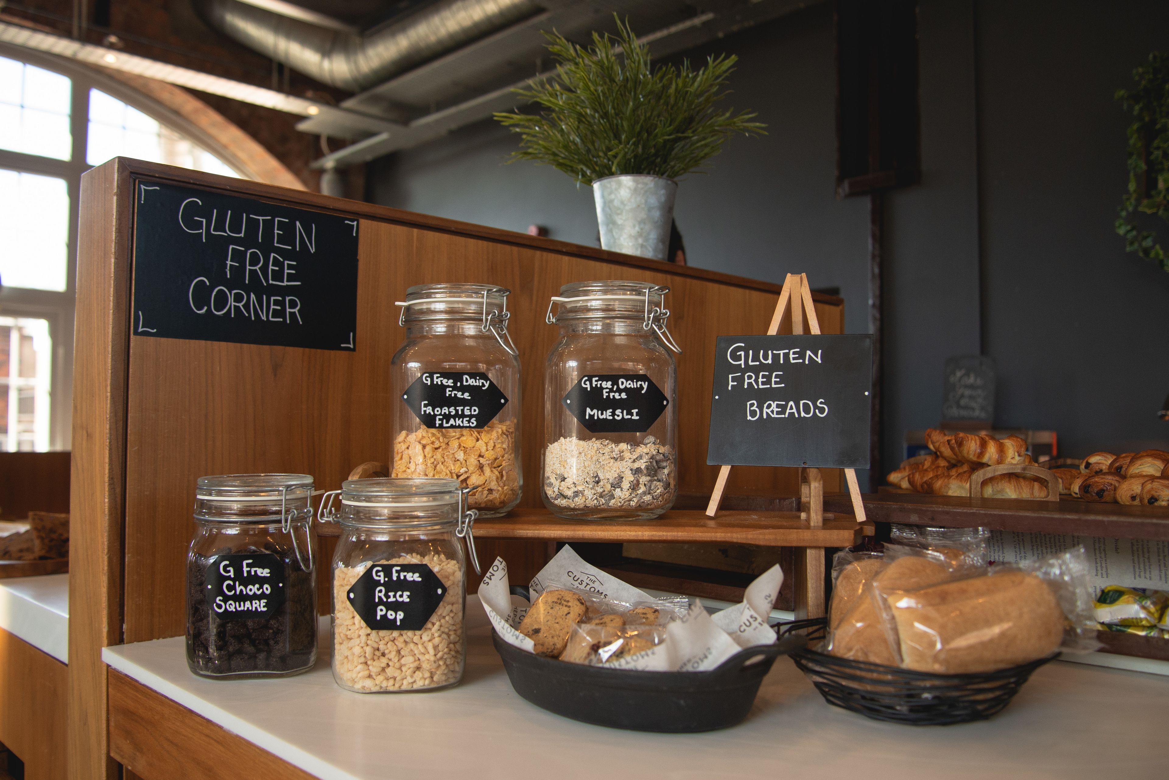 A gluten-free corner with labeled jars of snacks and a sign indicating gluten-free breads.