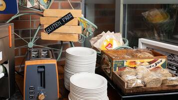 A kitchen area with a toaster, stacks of white plates, and gluten-free labeled items.