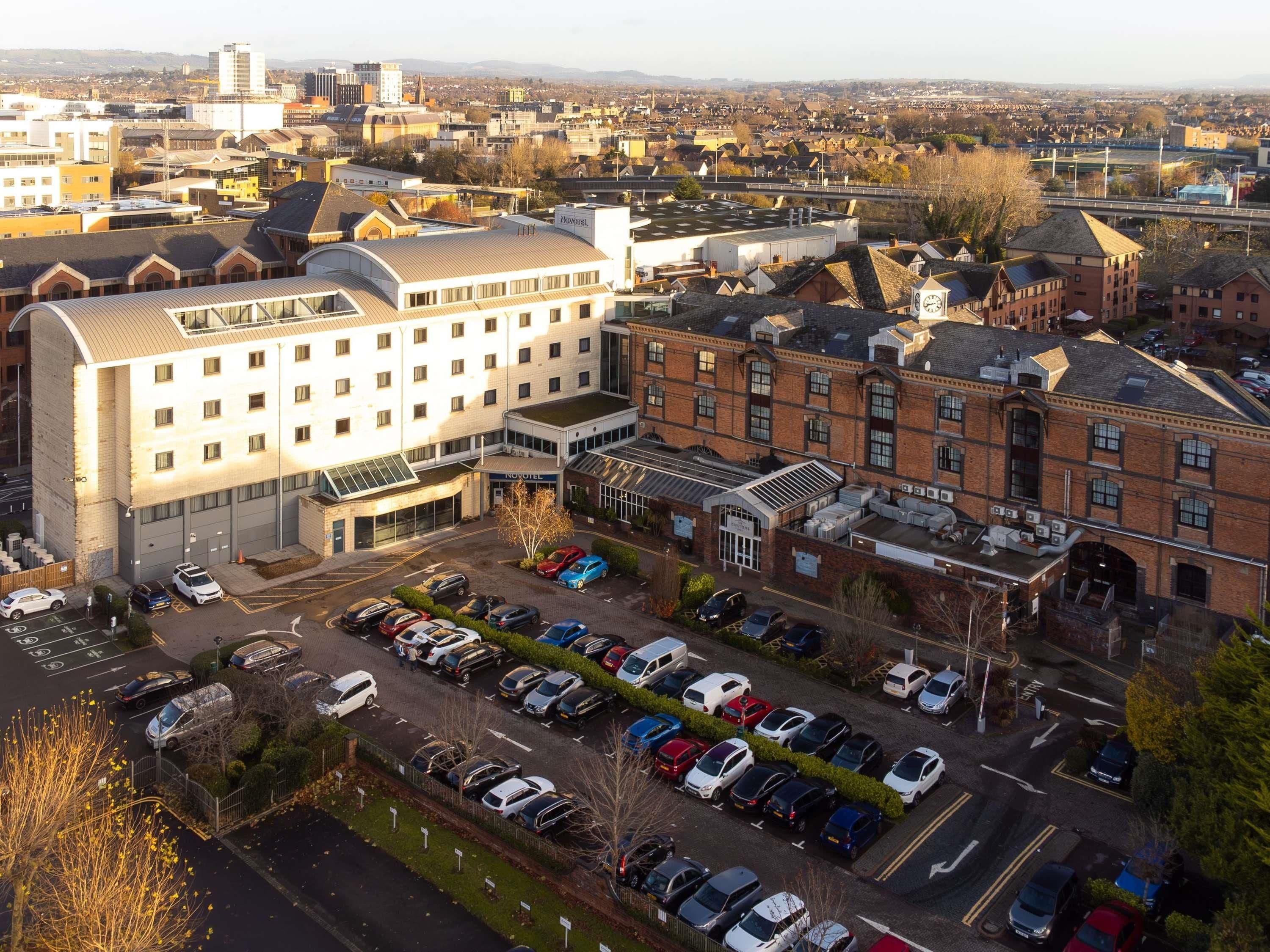 A hotel with a modern design, featuring a large parking lot and a prominent building with a curved roof.