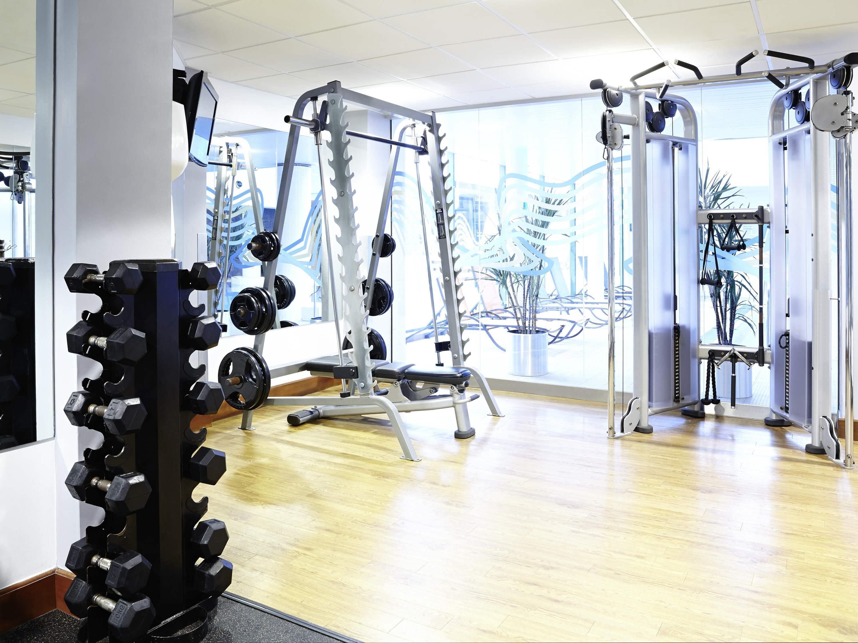 A gym with various exercise equipment, including dumbbells, weight machines, and a pull-up bar.