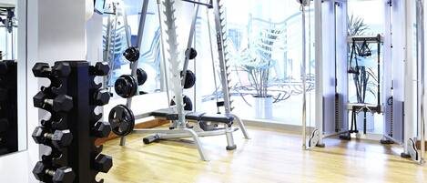 A gym with various exercise equipment, including dumbbells, weight machines, and a pull-up bar.