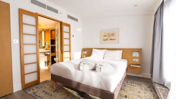 Habitación de hotel con cama, armario, baño y un cuadro en la pared.