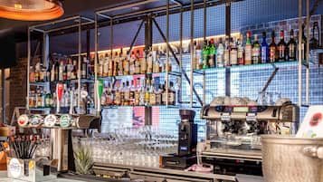 Un bar amb una varietat de botelles d'alcohol, una màquina de cafè i una vitrina de cristalleria.