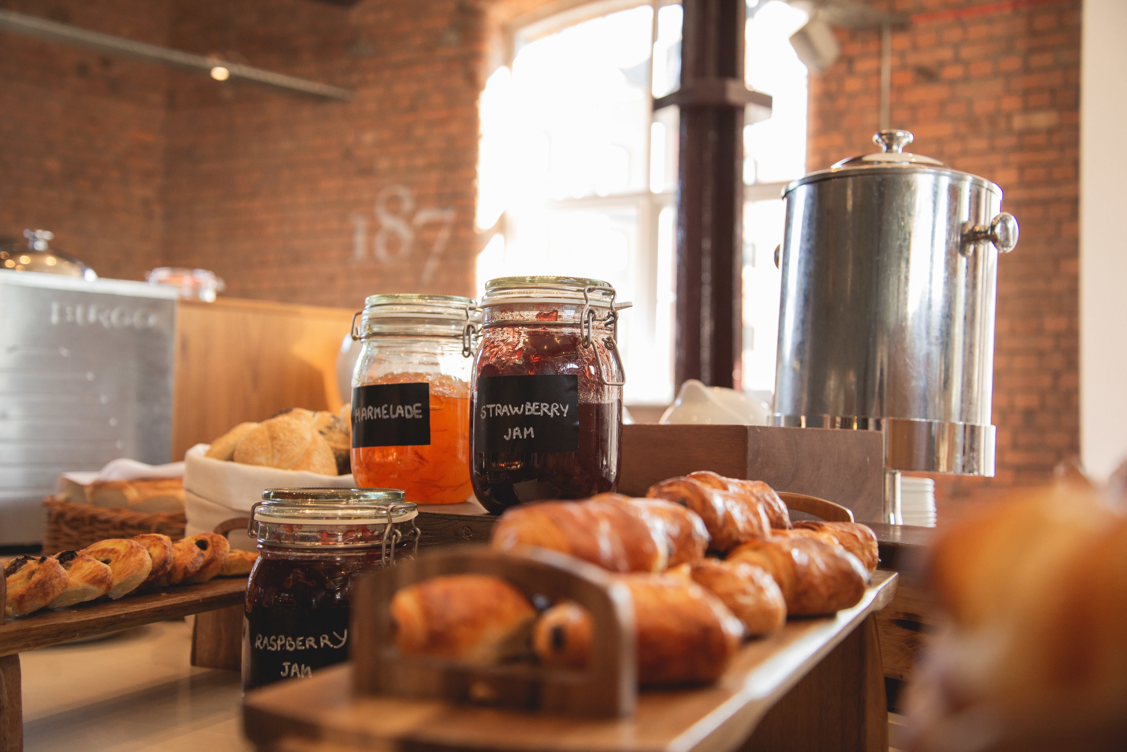 Ein Frühstücksbuffet mit Gebäck, Marmelade und einer Kaffeekanne.