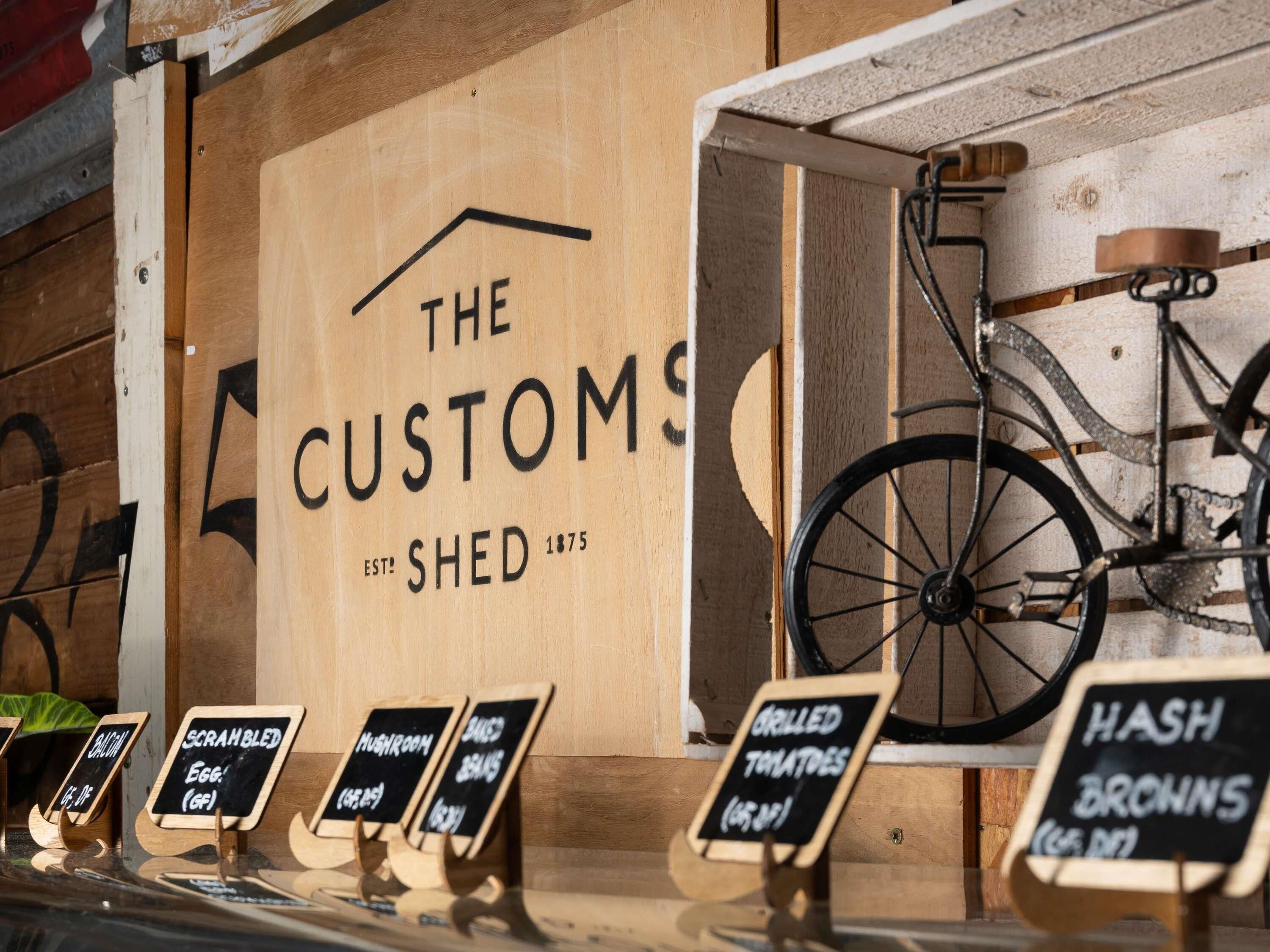 A wooden sign with 'The Custom Shed' and 'EST 1875' indicating a historical establishment.