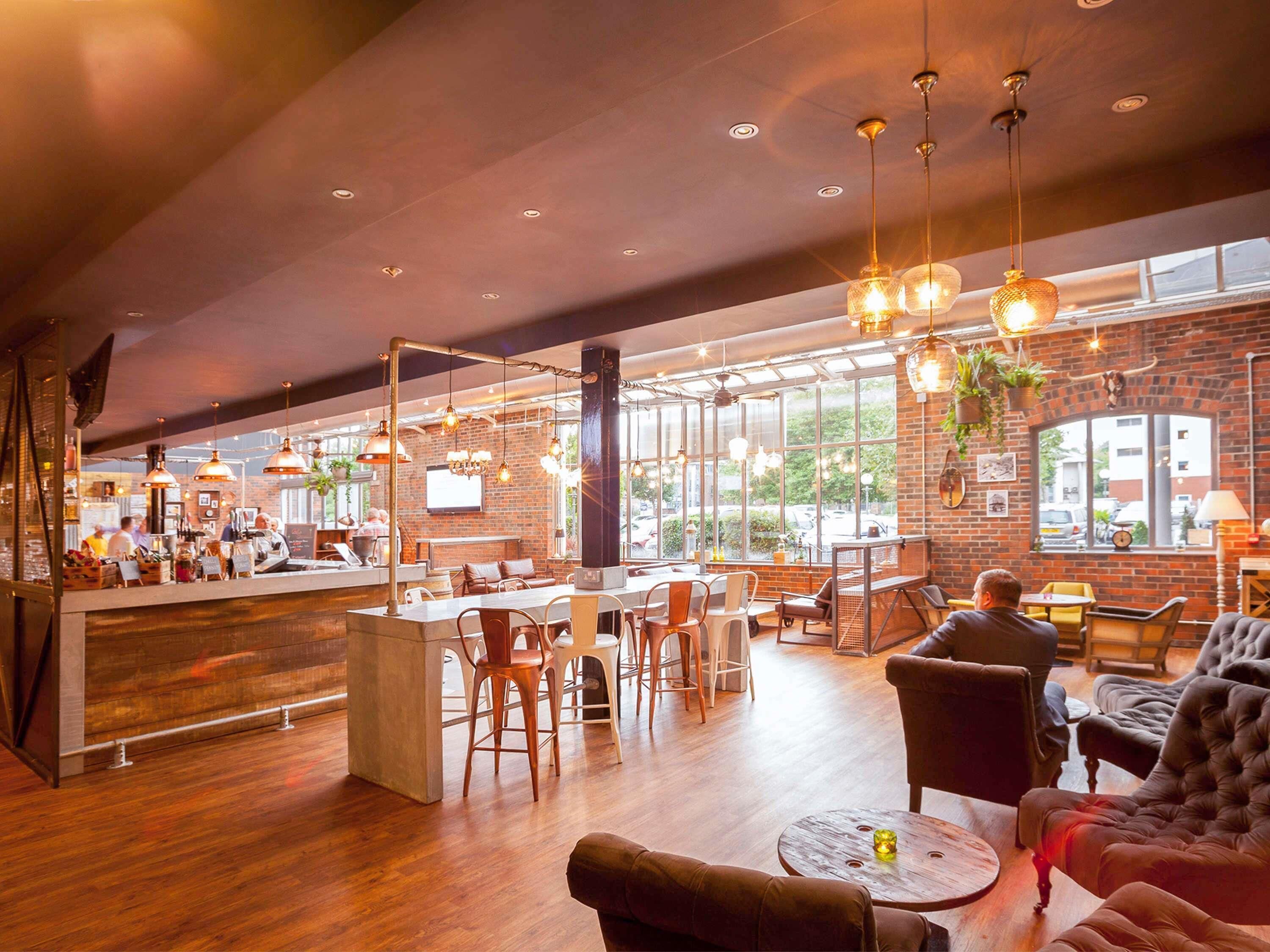 A spacious indoor area with a bar, seating, and large windows.