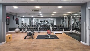 Une salle de sport équipée de matériel de musculation, d’haltères et d’appareils d’exercice.