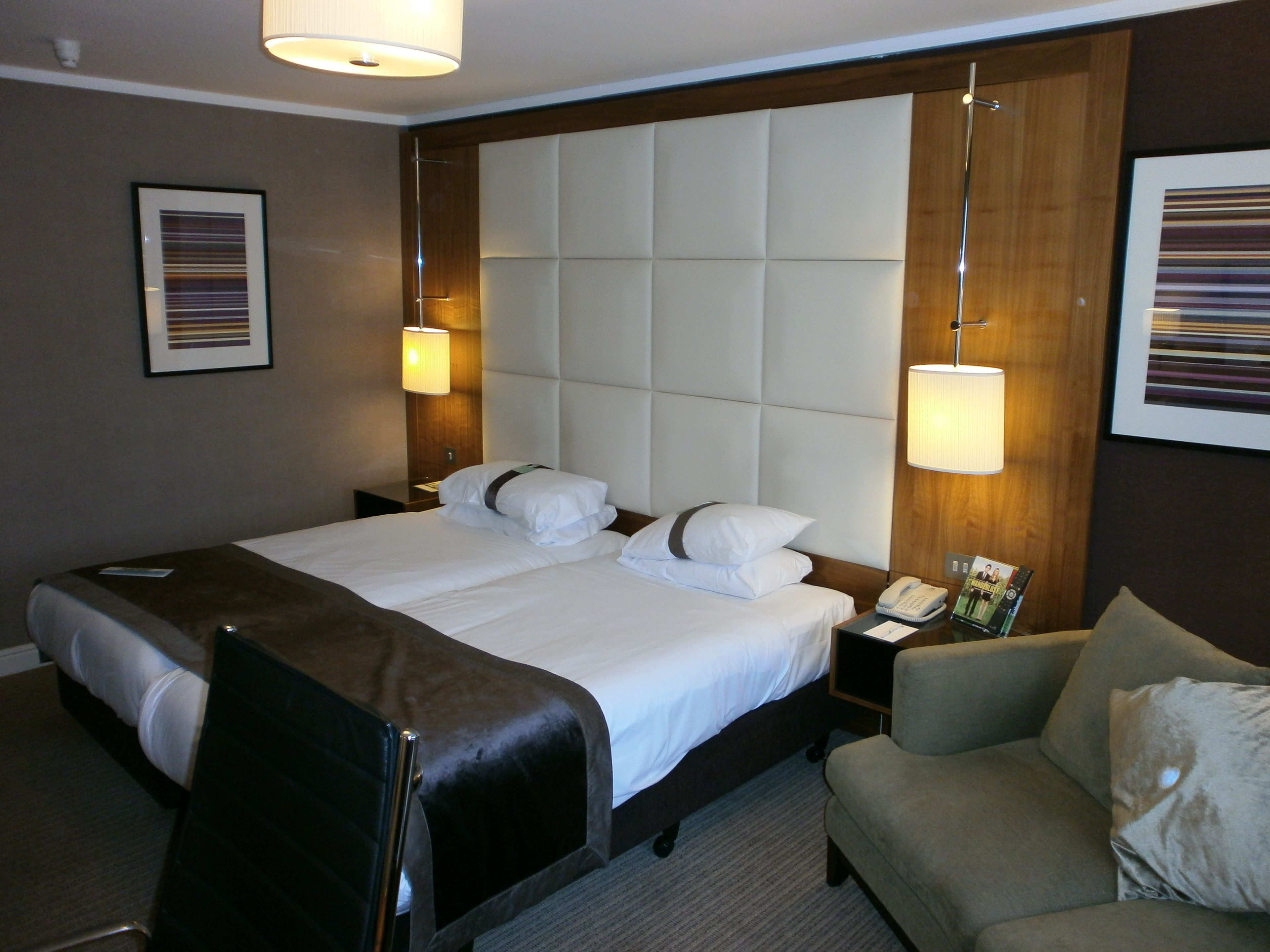 A hotel room with a large bed, two bedside tables, a chair, and a lamp.