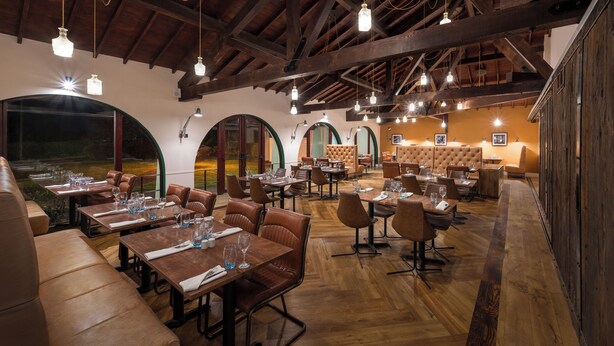 A restaurant with wooden beams, leather booths, and tables set for dining. - Holiday Inn Birmingham Bromsgrove by IHG (Bromsgrove)