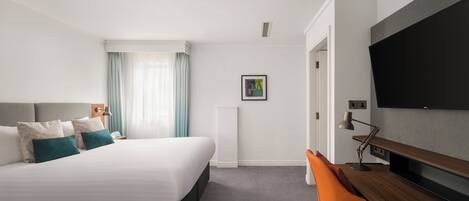 Een moderne hotelkamer met een groot bed, een bureau en een flatscreen televisie.