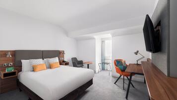 A modern hotel room with a large bed, a desk, a chair, and a TV mounted on the wall.