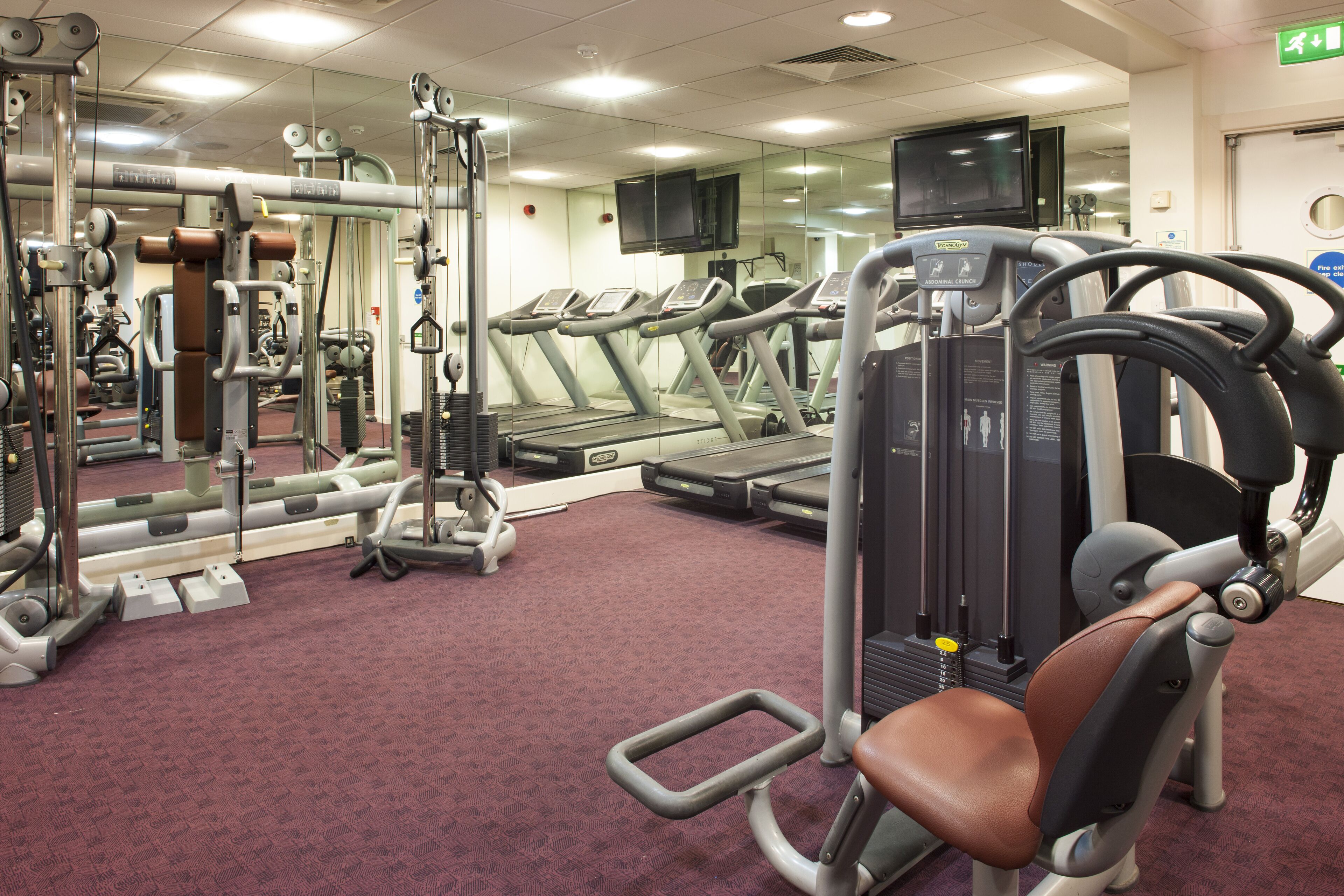 Un gimnasio con cintas de correr, máquinas de pesas y equipamiento de ejercicio.
