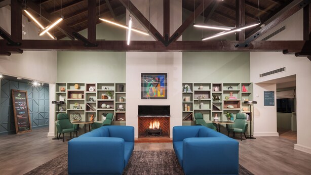 Un salon moderne avec des canapés bleus, une cheminée et des fauteuils verts.