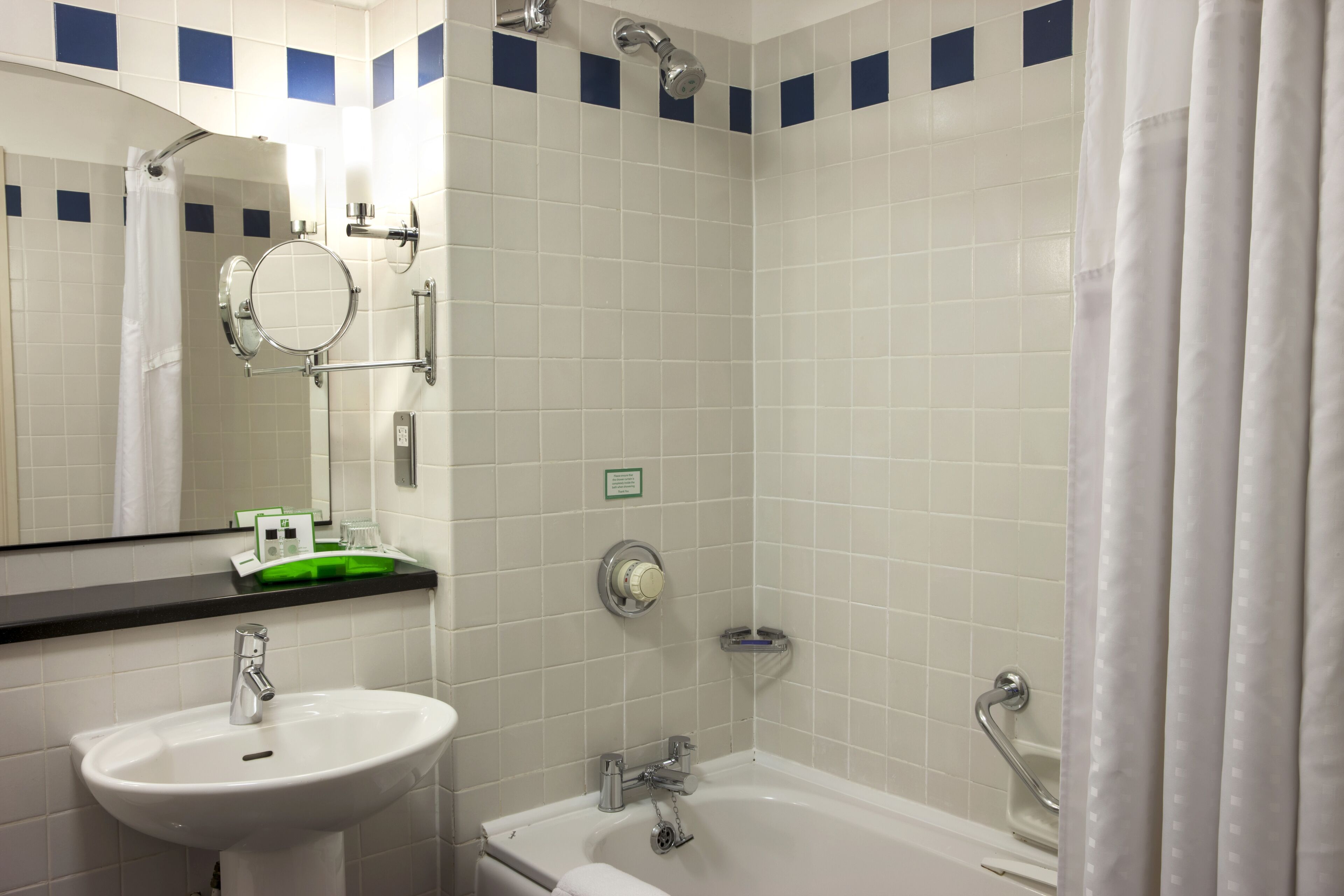 A bathroom with a sink, mirror, shower, and bathtub.
