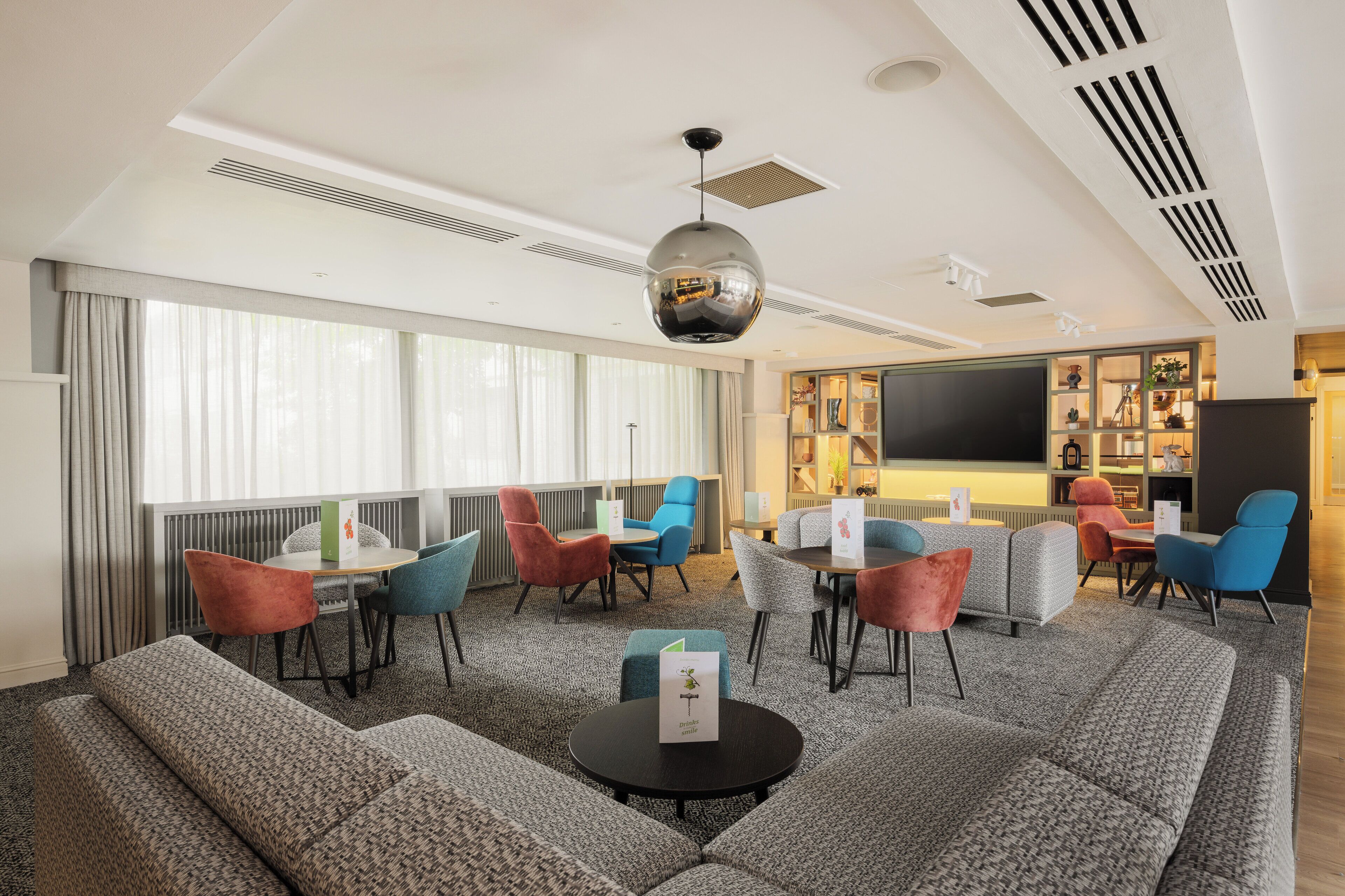 A modern hotel lobby with a seating area, large windows, and a disco ball.
