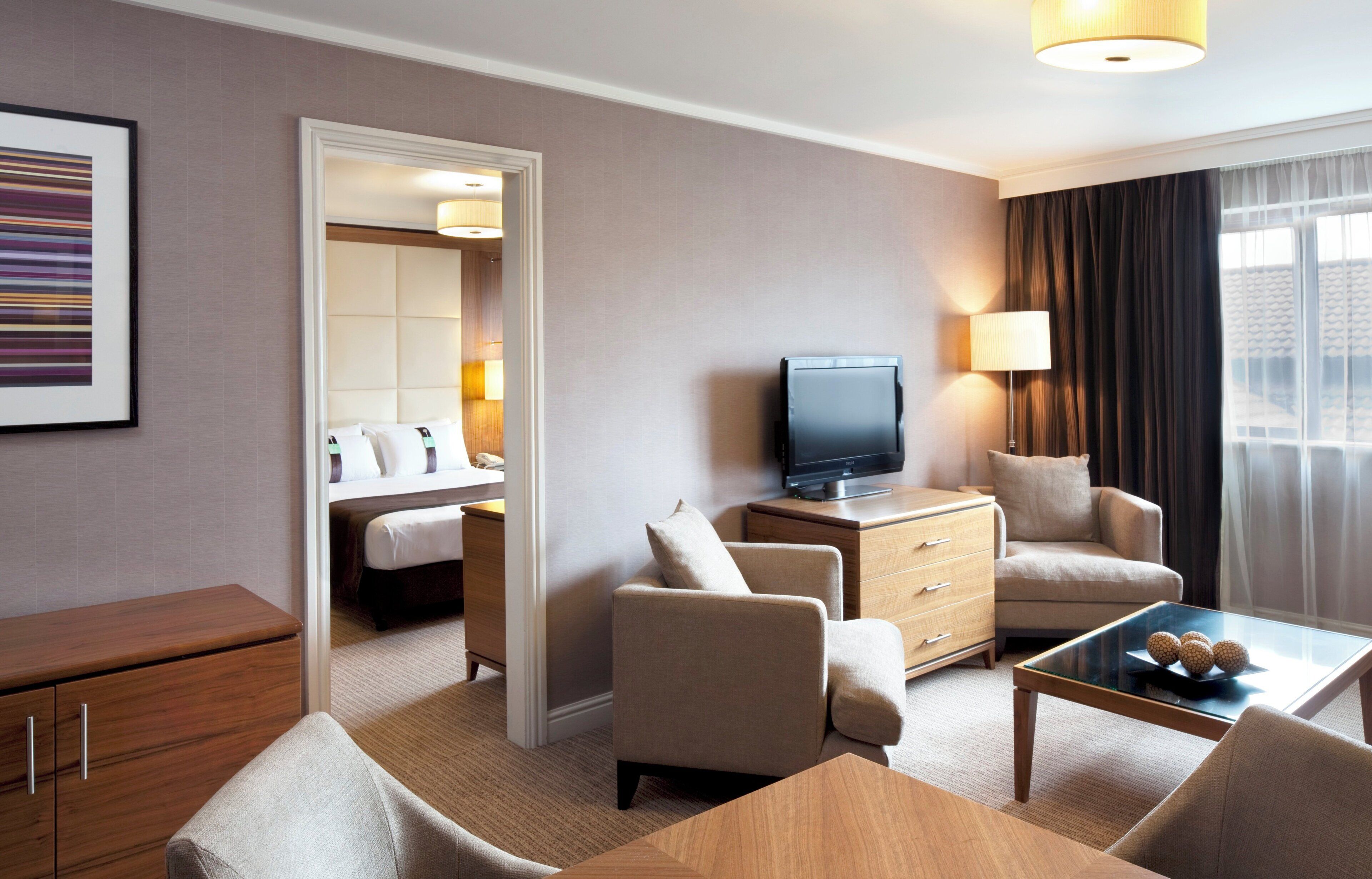 A hotel room with a bed, a television, a desk, a chair, and a coffee table.