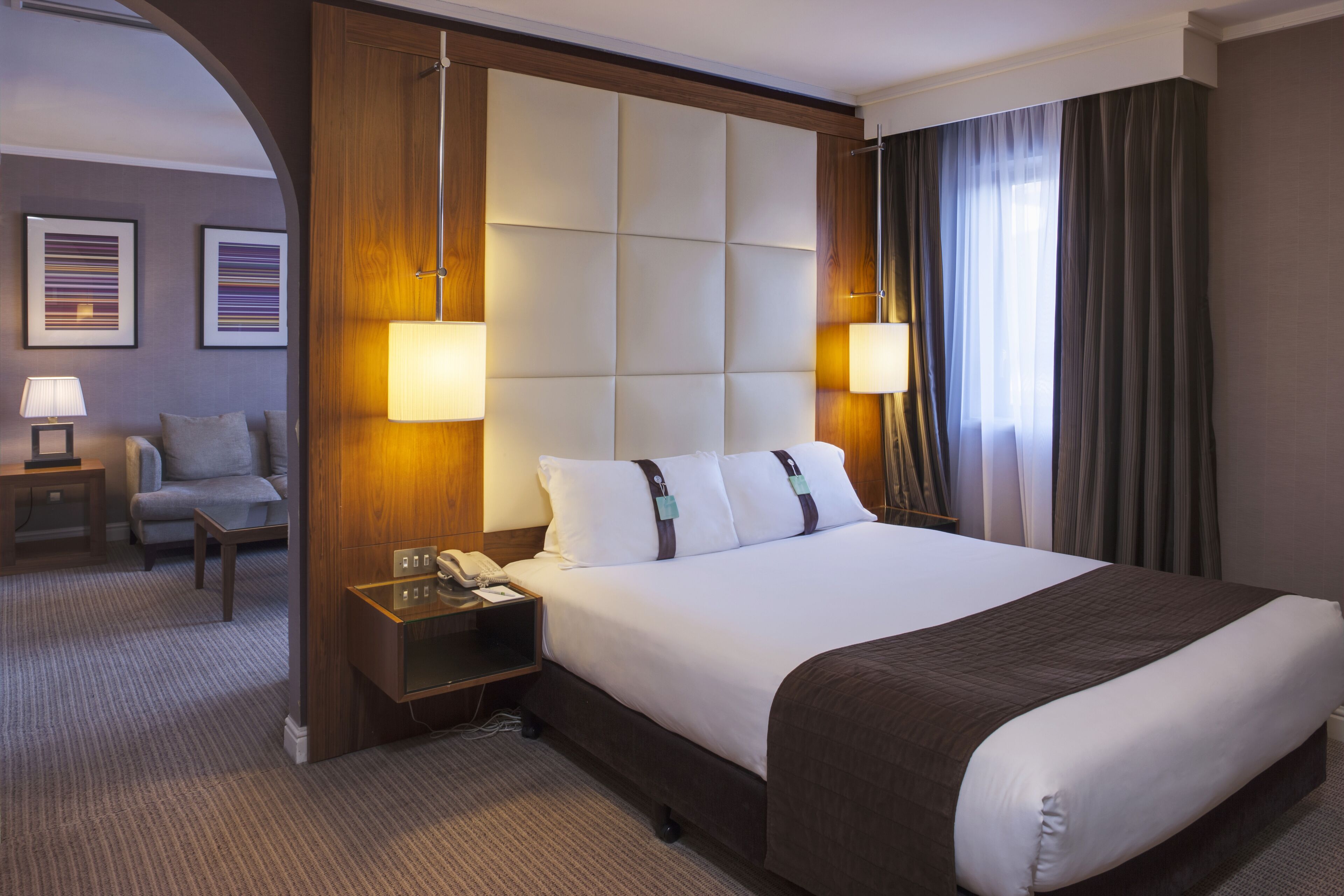 Una habitación de hotel con una cama grande, dos lámparas de noche, una mesita de noche, una silla y un escritorio.