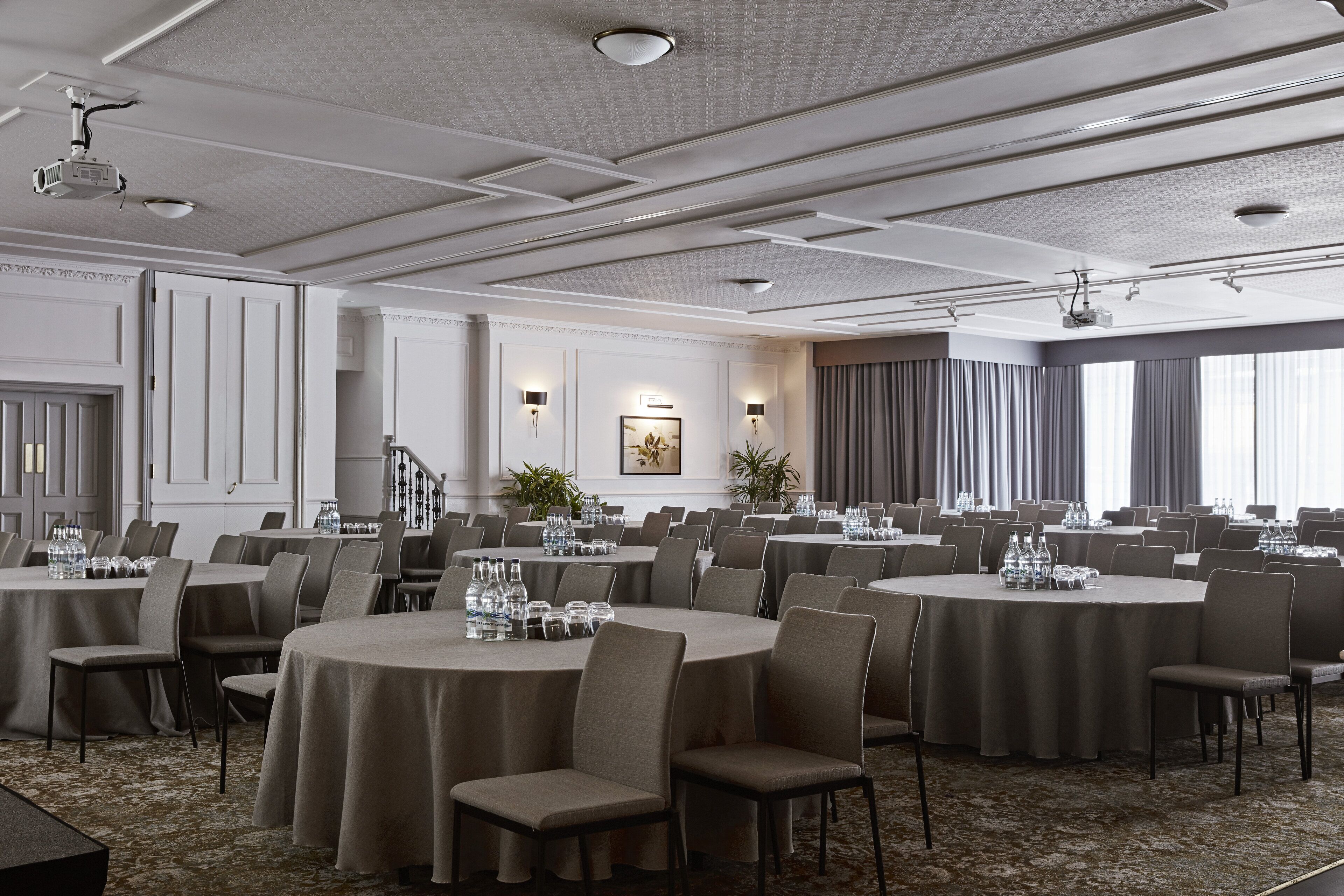 A conference room with round tables, chairs, and a carpeted floor.