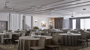 A conference room with round tables, chairs, and a carpeted floor.