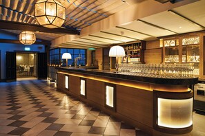 A bar area with a checkered floor, bar counter with a lighted base, and overhead lighting fixtures. - Kimpton Charlotte Square by IHG (Edinburgh)