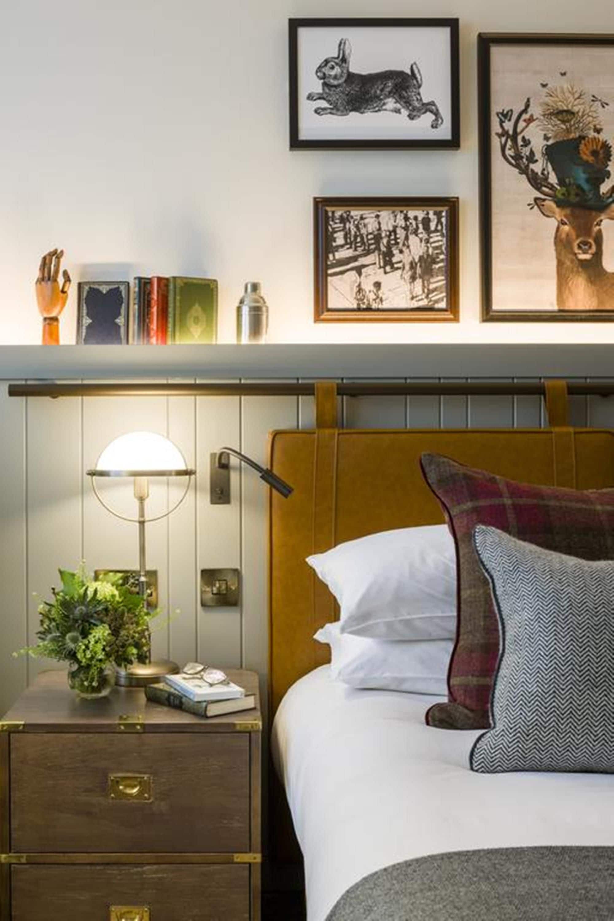 A neatly arranged bedroom with a bed, bedside table, lamp, and framed artwork on the wall.