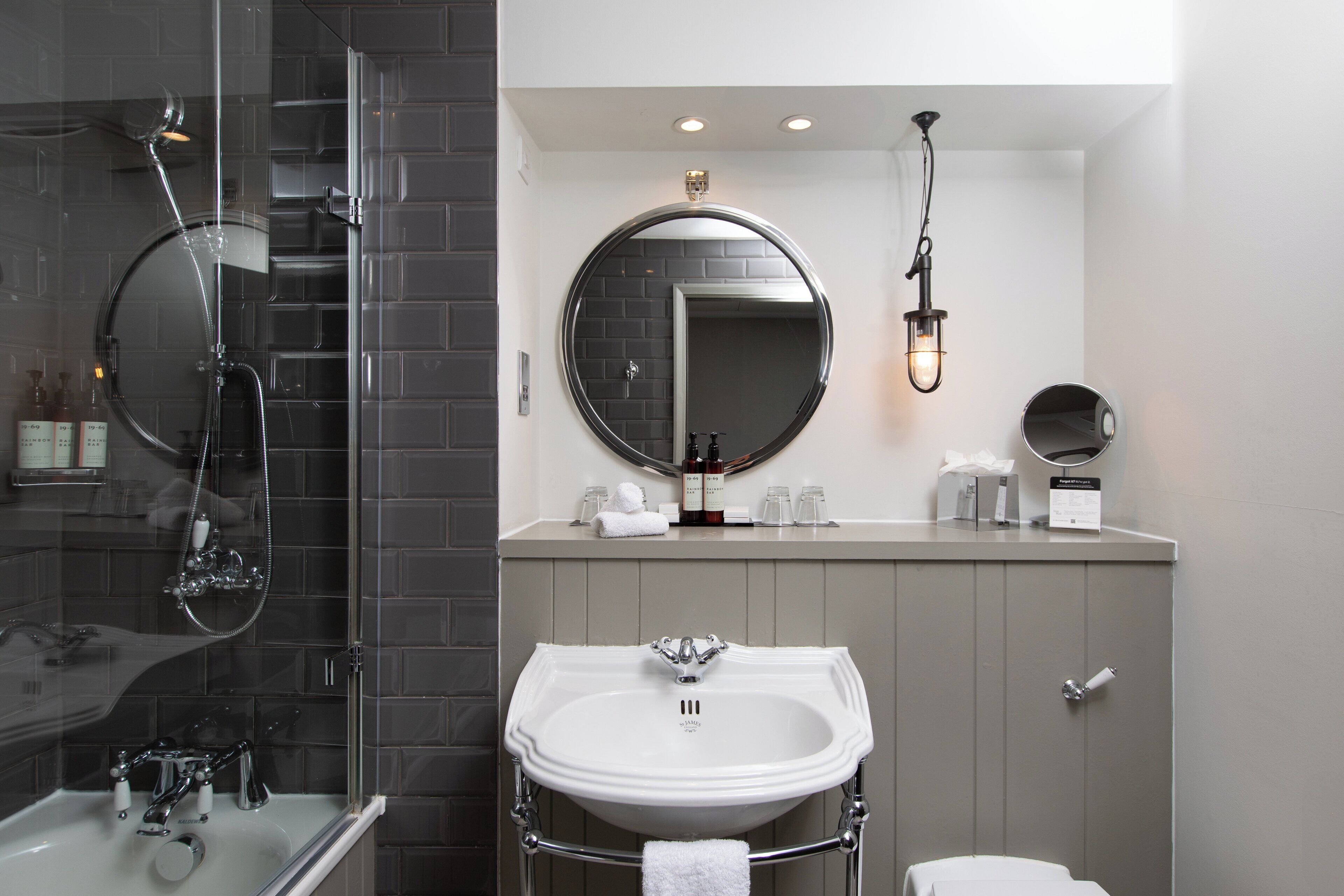 A modern bathroom with a glass-enclosed shower, a white sink, and a large mirror.