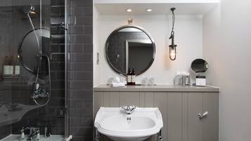 A modern bathroom with a glass-enclosed shower, a white sink, and a large mirror.