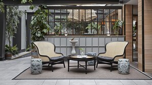 A modern indoor seating area with two chairs and a round table, surrounded by potted plants and a glass ceiling. - Kimpton Charlotte Square by IHG (Edinburgh)