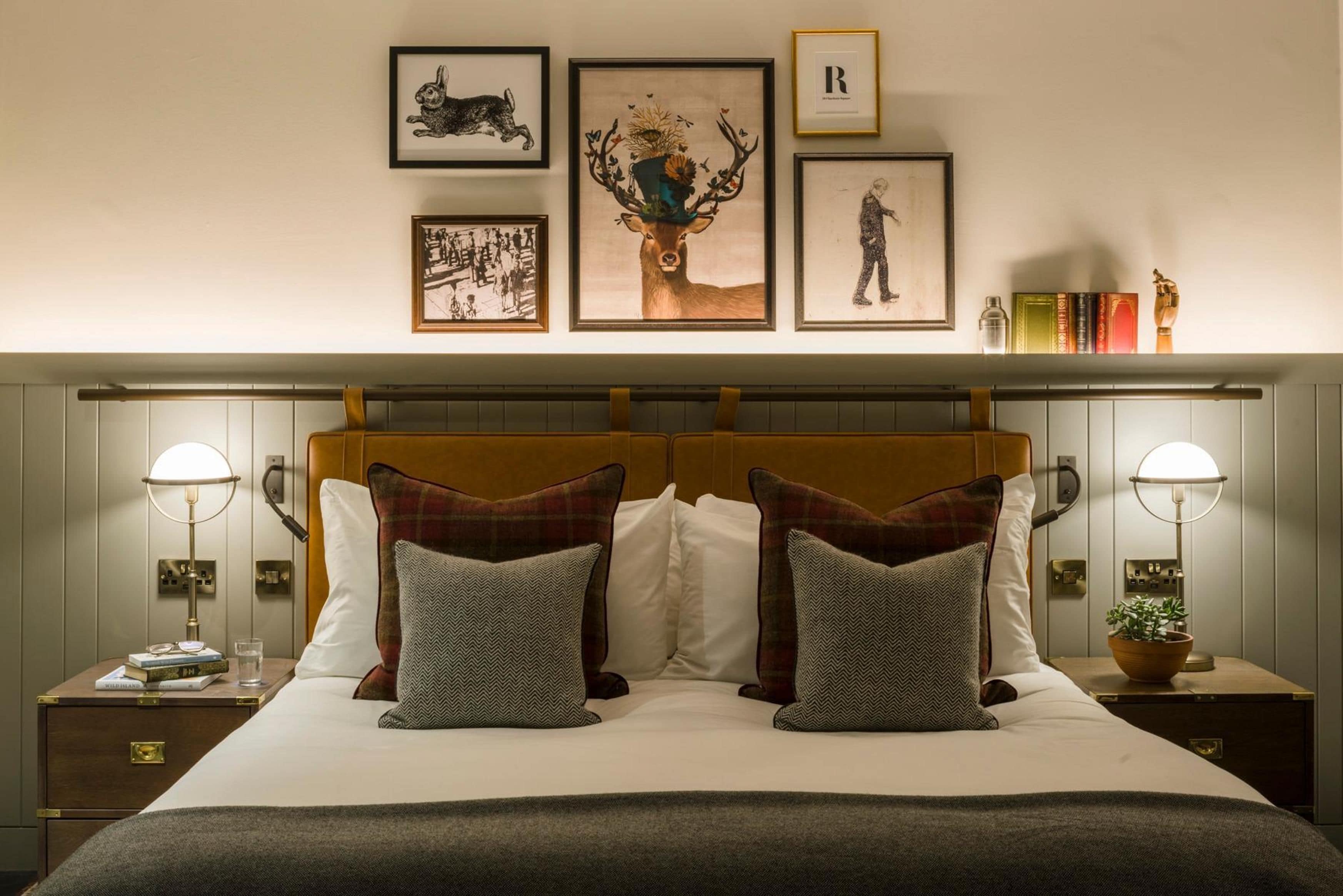 A neatly made double bed with a plaid headboard, two bedside tables with lamps, and framed artwork on the wall.