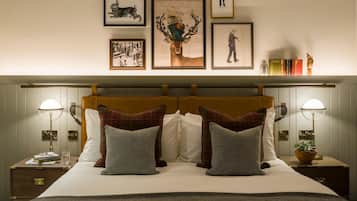 Een net opgemaakt tweepersoonsbed met een geruit hoofdbord, twee nachtkastjes met lampen en een lijst met kunstwerk aan de muur.
