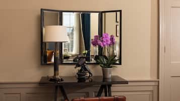 A room with a desk, a lamp, a mirror, a potted plant, and a chair.