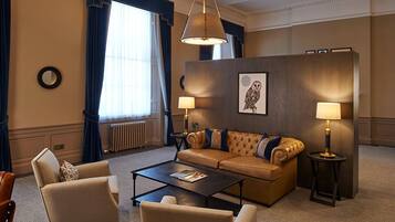 Ein Hotelzimmer mit einer großen Couch, zwei Sesseln, einem Couchtisch und zwei Lampen.