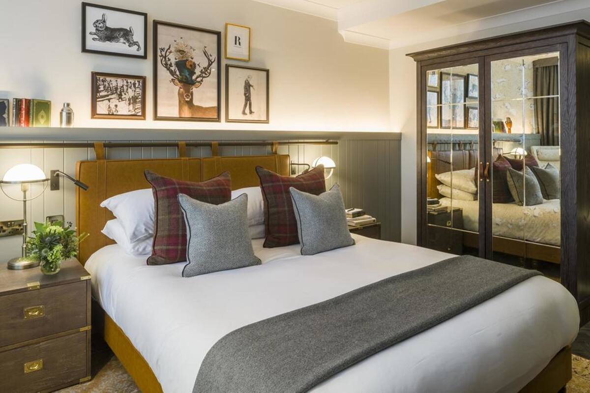 Een netjes ingerichte slaapkamer met een groot bed, een houten hoofdbord, een nachtkastje met lamp en een garderobe met glazen deuren.